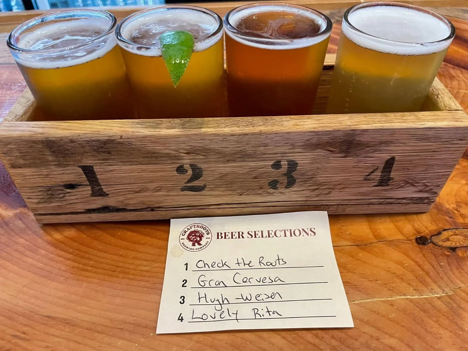 Four golden and amber beers in a wooden tasting-flight tray at CraftRoots