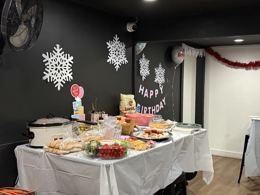A birthday buffet table with decorations and a white tablecloth