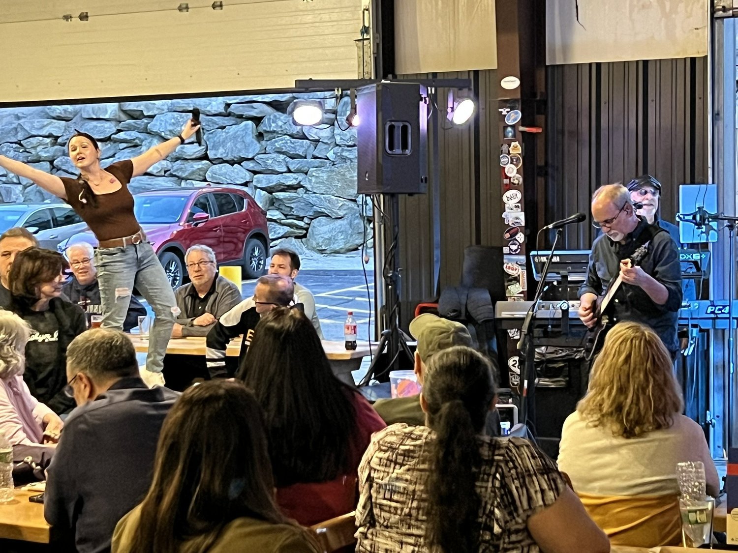 Live music performance at a restaurant with a singer, guitarist, and audience enjoying the show.